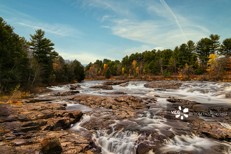 秋季，加拿大，森林中，蓝天下，河流在岩石上流淌的风景图片素材