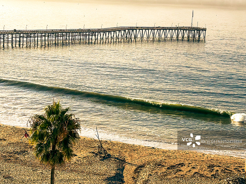 金色时分，宁静的海滩上，长长的码头伸向平静的海洋，地点：美国加利福尼亚州文图拉图片素材