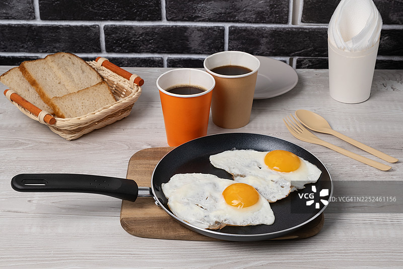 俯视角度拍摄的简单早餐，包括煎蛋、吐司和咖啡，摆放在木桌上图片素材