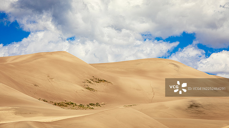 在美国莫斯卡广阔的沙漠沙丘上，蓝天白云下的壮丽景色图片素材