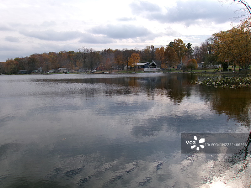 秋季树木倒映在宁静湖面上的美景，湖岸边坐落着房屋，汉密尔顿，美国图片素材