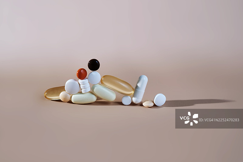 俯视角度拍摄的各种药丸和胶囊，背景为中性色，象征着医药和医疗保健图片素材