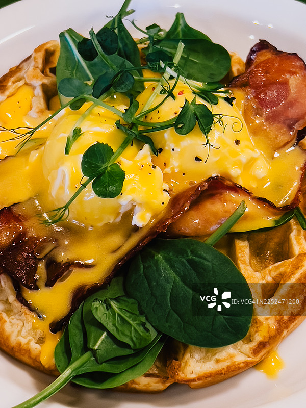 美味的华夫饼配水波蛋、荷兰酱、培根和新鲜蔬菜图片素材