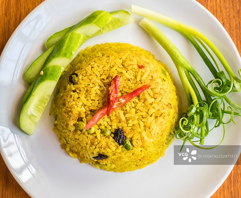 白盘子里的泰式黄咖喱饭，配有新鲜黄瓜和葱图片素材