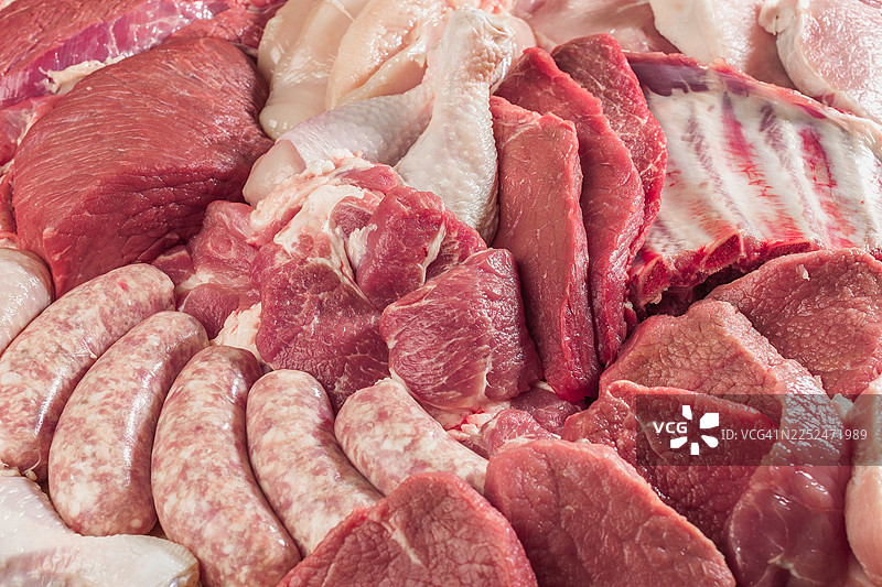 各种新鲜的生肉，包括牛肉、鸡肉、猪排和香肠，已准备好烹饪图片素材