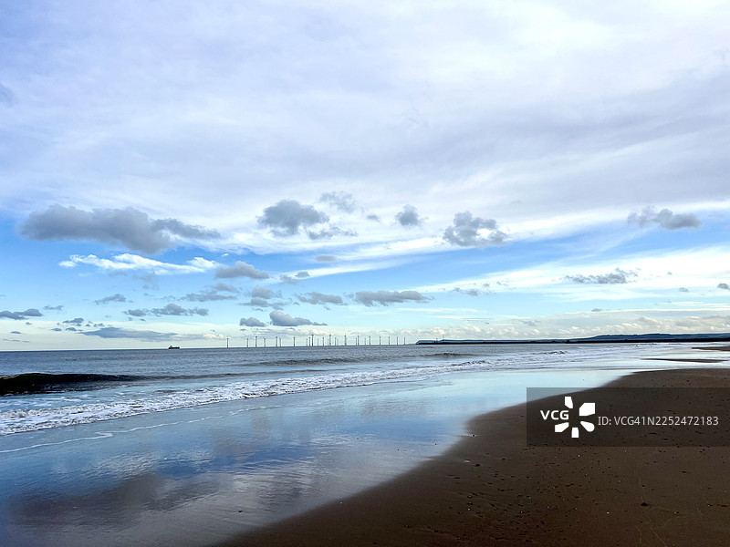 英国哈特尔浦特，蒂斯湾，多云天空下的海滩，海浪和风力涡轮机的风景图片素材