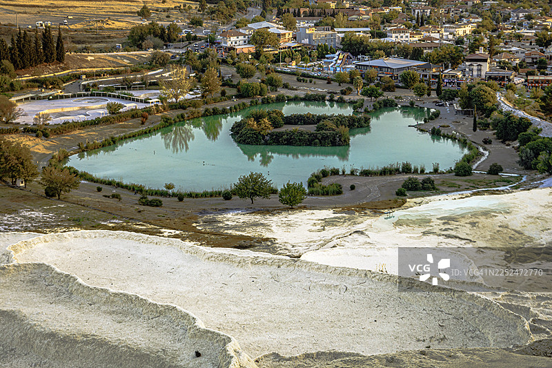 土耳其棉花堡（Pamukkale）的石灰华梯田和城镇环绕的碧绿湖泊的高角度视角，棉花堡马哈勒西，土耳其图片素材