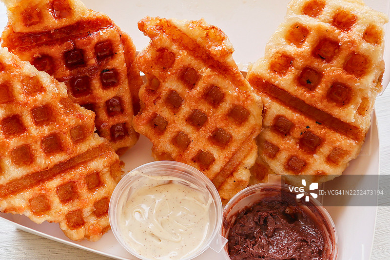桌上摆放着美味的金黄色华夫饼，旁边配有蘸酱，特写镜头图片素材