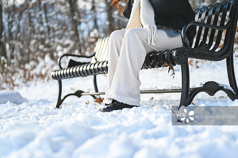 一位女士在公园长椅上享受冬日时光图片素材
