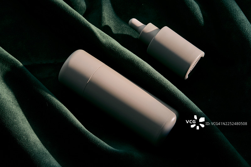 天鹅绒上的护肤化妆品精华液瓶和滴管图片素材