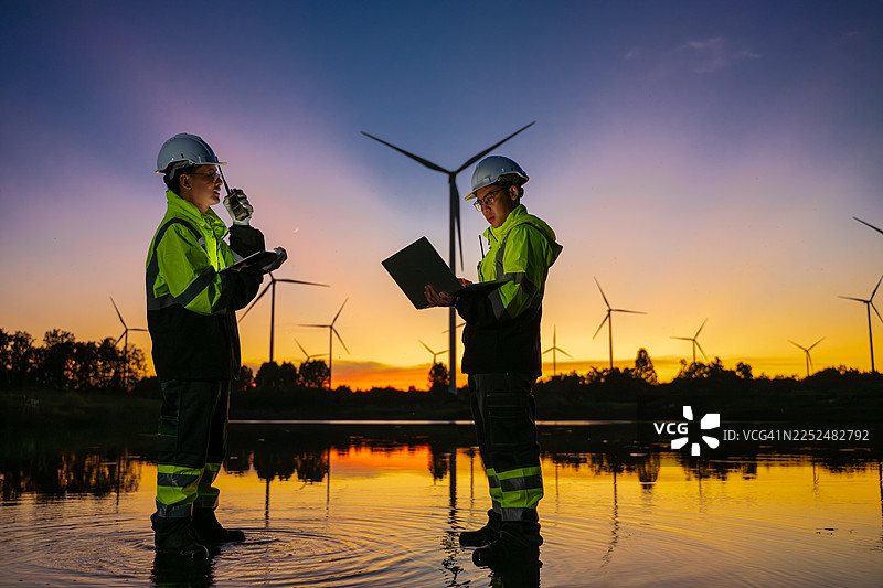 剪影工程师在风电场工作，监控可再生能源运营，风力涡轮机象征着可持续技术和清洁能源解决方案，以及可再生能源领域的环境责任。图片素材