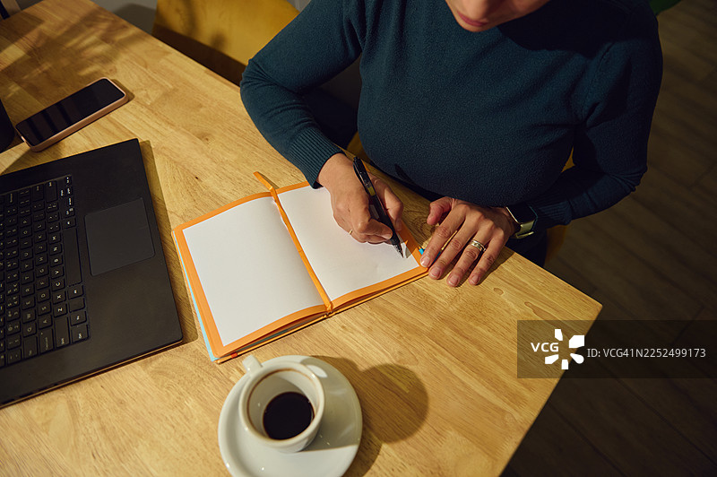 在咖啡馆商务写作：一位现代中东女性使用笔记本电脑和手提电脑远程办公图片素材