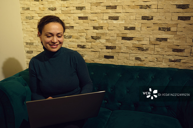 在中东女子在现代舒适的咖啡馆内使用笔记本电脑远程办公，营造出放松的氛围图片素材