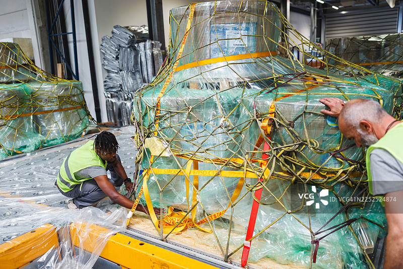 专业的团队确保在光线充足的机场仓库环境中货物的安全图片素材