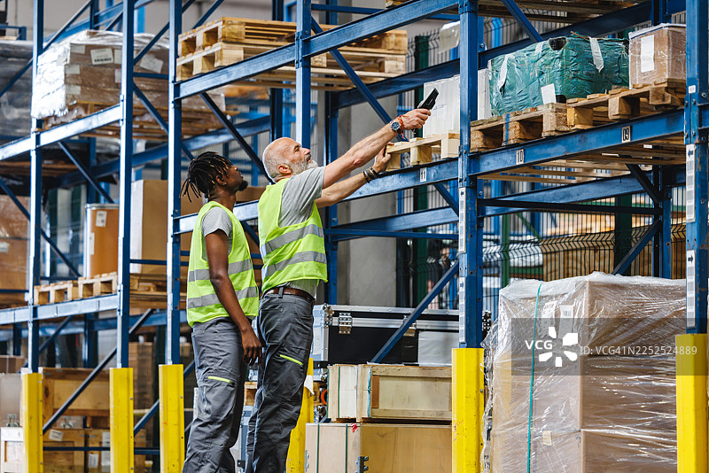分拣中心过道里，多元化的仓库团队正在协作进行库存任务图片素材