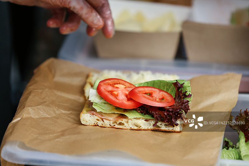 厨师正在制作火腿、奶酪、番茄和绿色沙拉的佛卡夏三明治图片素材