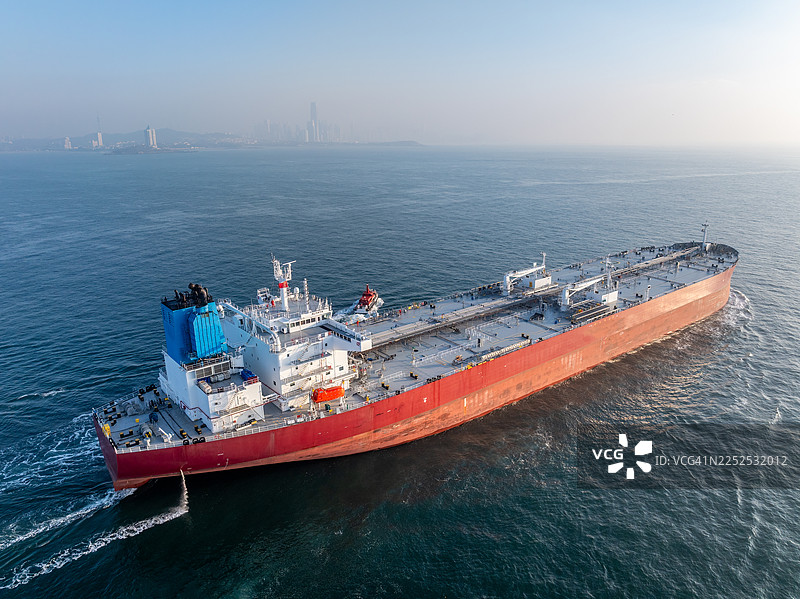 一艘巨型原油油轮驶过青岛市天际线前方图片素材