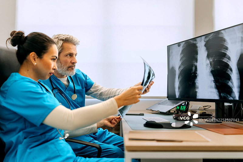 医务人员在办公桌前查看肺部X光片图片素材