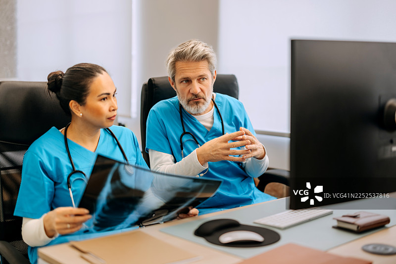 医生们坐在桌前分析肺部X光片图片素材