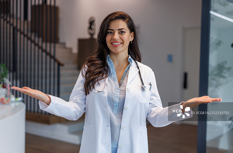 一位面带微笑的女医生敞开双臂欢迎人们图片素材