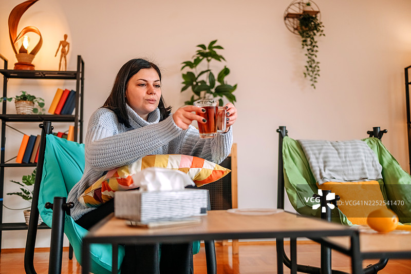 女子在客厅家中查看健康状况，手中拿着茶杯图片素材
