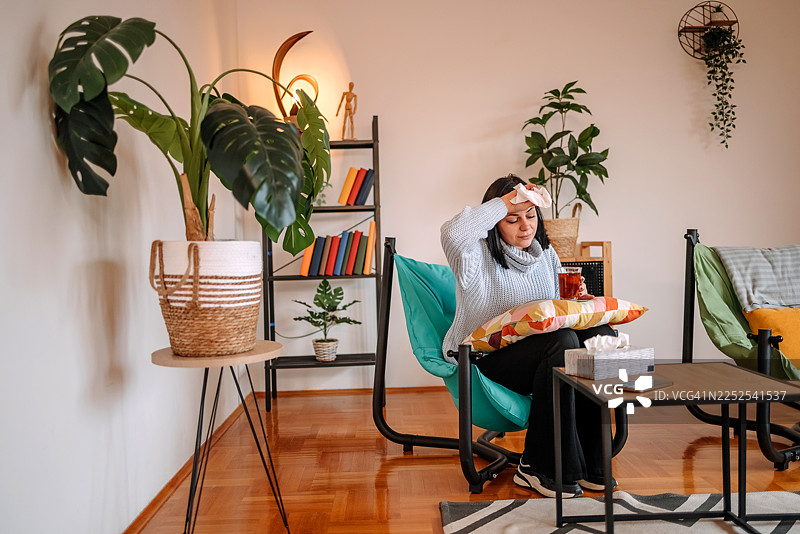 一位女士在家里的客厅用温度计检查健康状况图片素材