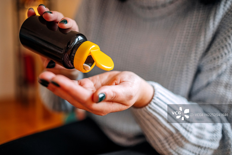 一位女士在家里的客厅里查看自己的健康状况，并在服药前查看药瓶。图片素材