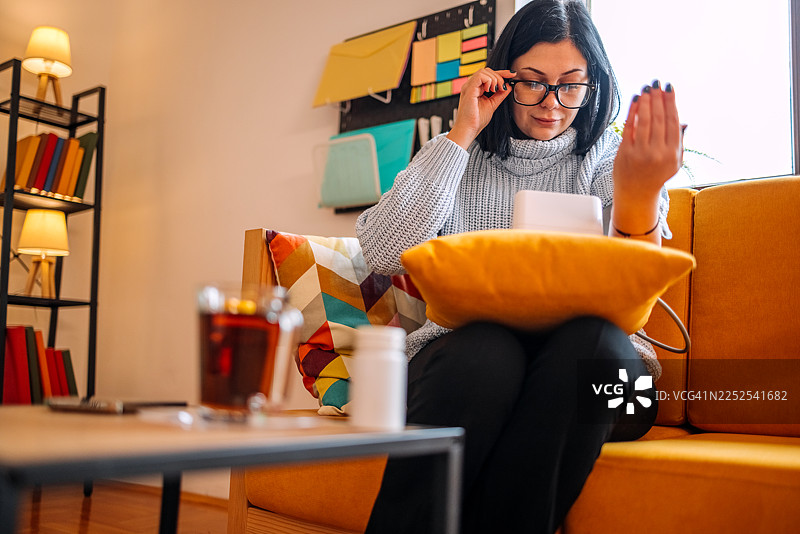 一位女士在家里的客厅使用血压计检查她的健康状况图片素材