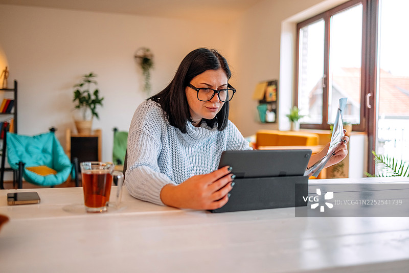 一名女性在家中的客厅查看X光片，关注自己的健康状况图片素材