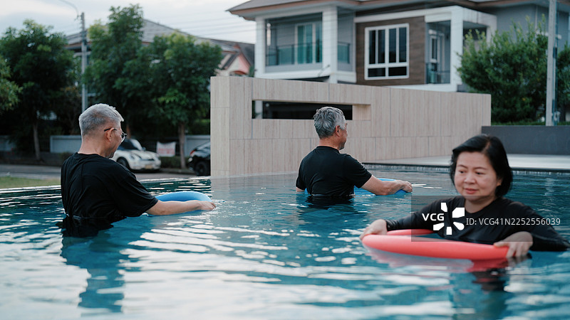 一群老年人在游泳池中使用浮条进行物理治疗锻炼图片素材