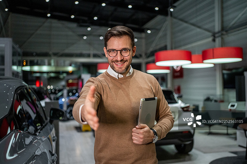 在现代展厅中，汽车销售人员伸出手准备握手图片素材