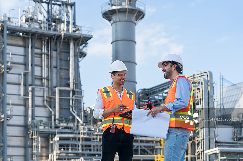 工程师在炼油厂讨论计划。图片素材