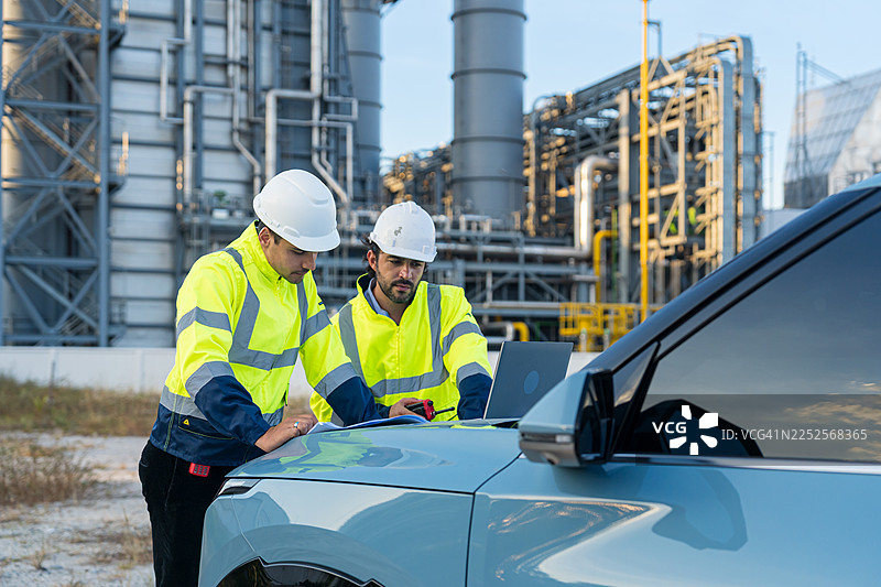 工程师在工业炼油厂使用笔记本电脑进行检查讨论图片素材