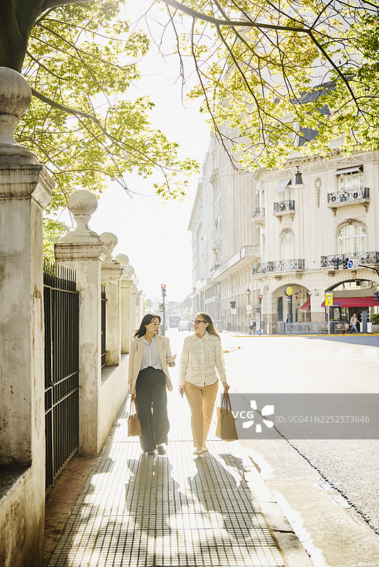 女性同事在市中心街道上行走的广角镜头图片素材