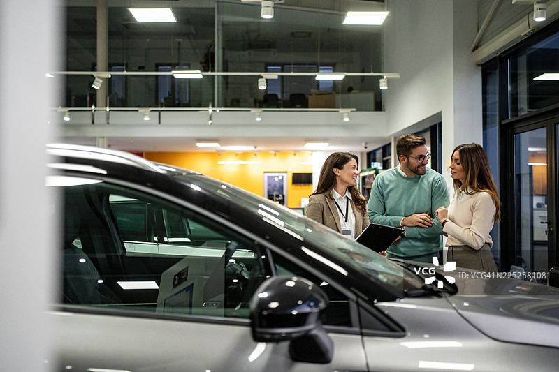 销售人员在汽车经销商处协助一对夫妇购买新车图片素材