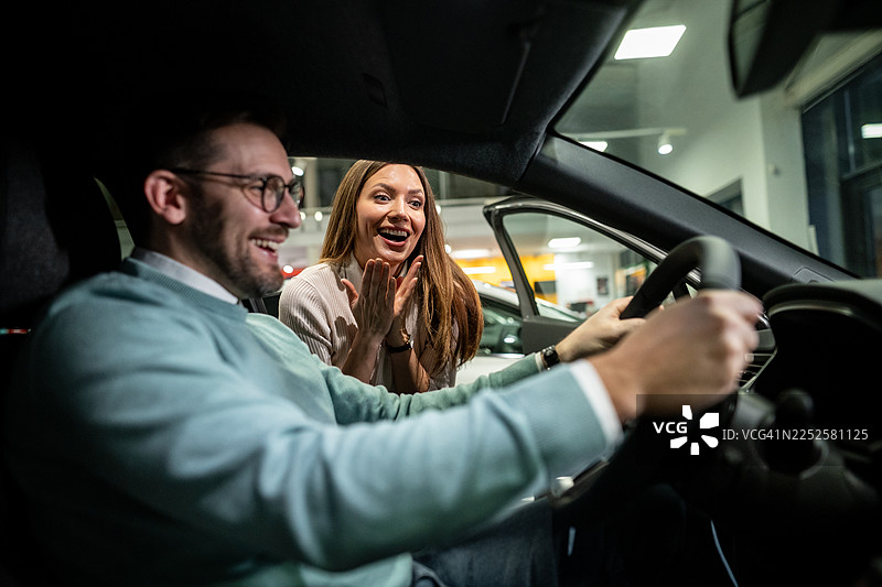 一对快乐的夫妇在经销商展厅购买新车图片素材