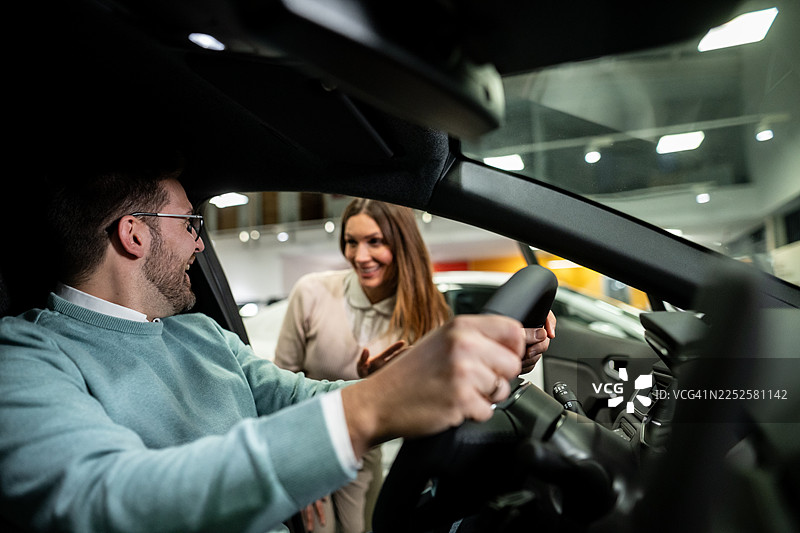 年轻夫妇在展厅考虑购买新车图片素材