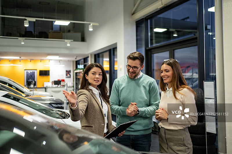 汽车销售员向一对幸福的夫妇展示新车图片素材