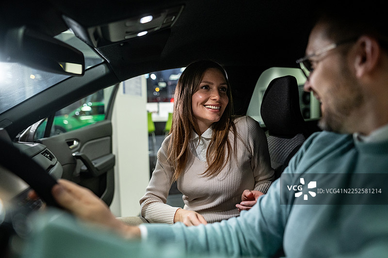 快乐的夫妇在展厅里看着新车图片素材