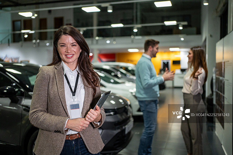 女性汽车销售员在汽车展厅内微笑图片素材