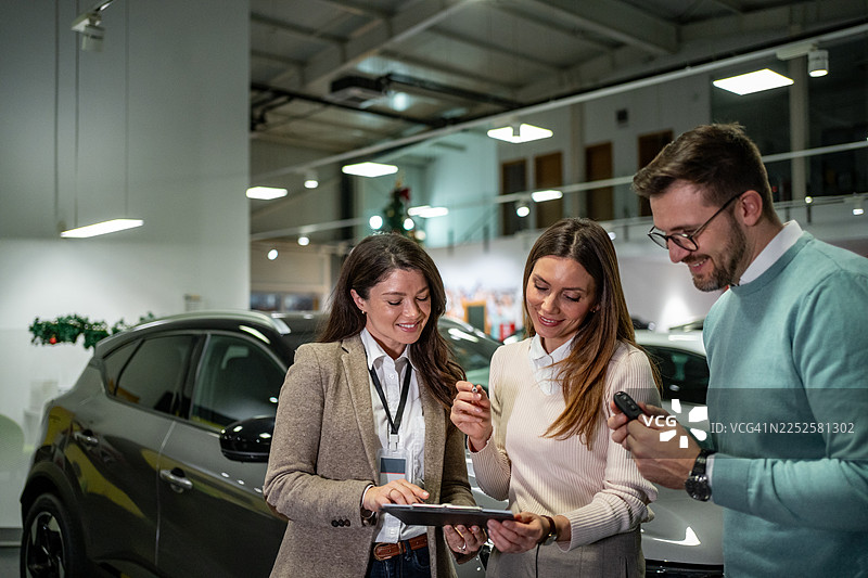 销售人员在展厅帮助夫妇挑选新车图片素材