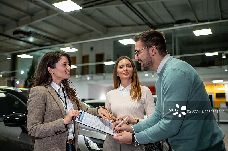 一对情侣在汽车经销商处签署购车协议图片素材