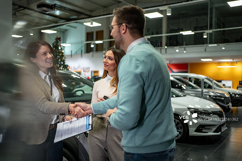 汽车销售人员在交易过程中与男性顾客握手图片素材