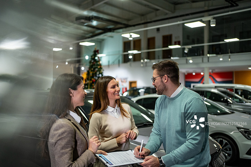 情侣在汽车经销商的圣诞促销活动上签署购车合同图片素材