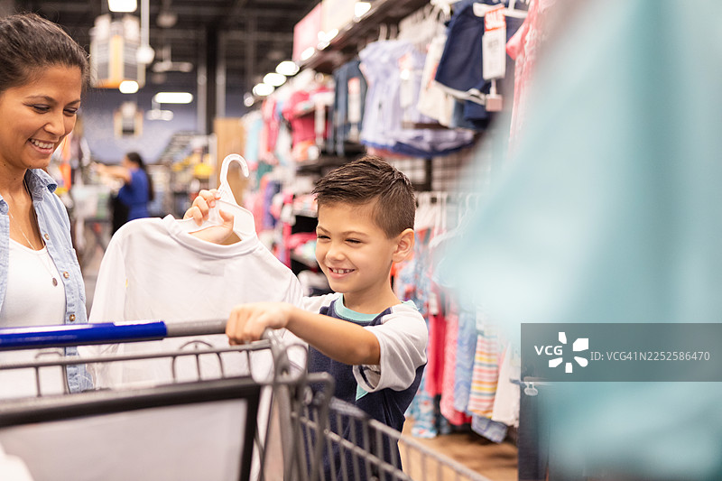 一位母亲和她的儿子在一家零售店里购物时微笑着图片素材