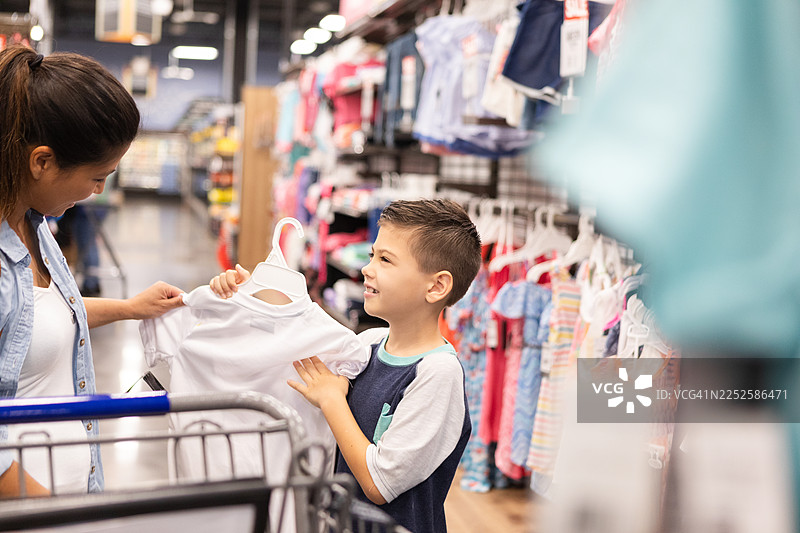 一位母亲和儿子在明亮的商店过道里开心地选购衣服图片素材