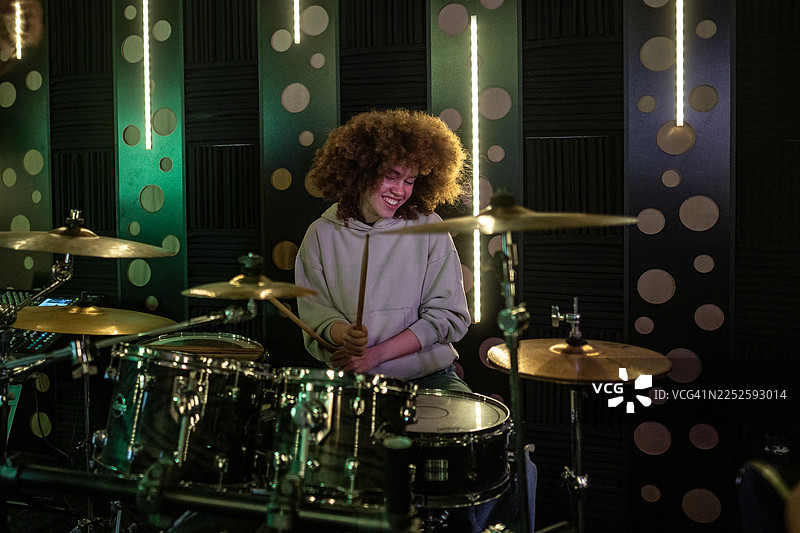 年轻女子在音乐工作室里打鼓，享受音乐图片素材