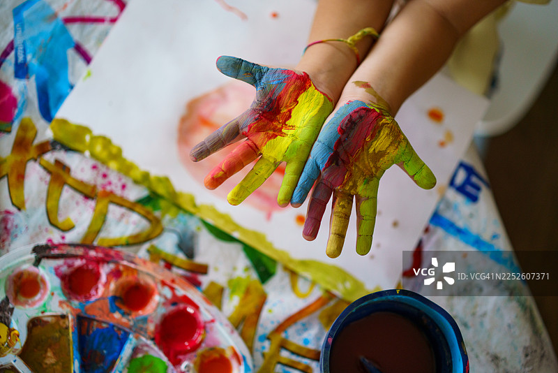 特写：孩子的手上沾满了彩色颜料，正在玩艺术创作。图片素材