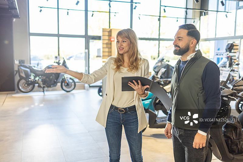 明亮的展厅里，业务员们正在讨论摩托车选项的商务会议图片素材