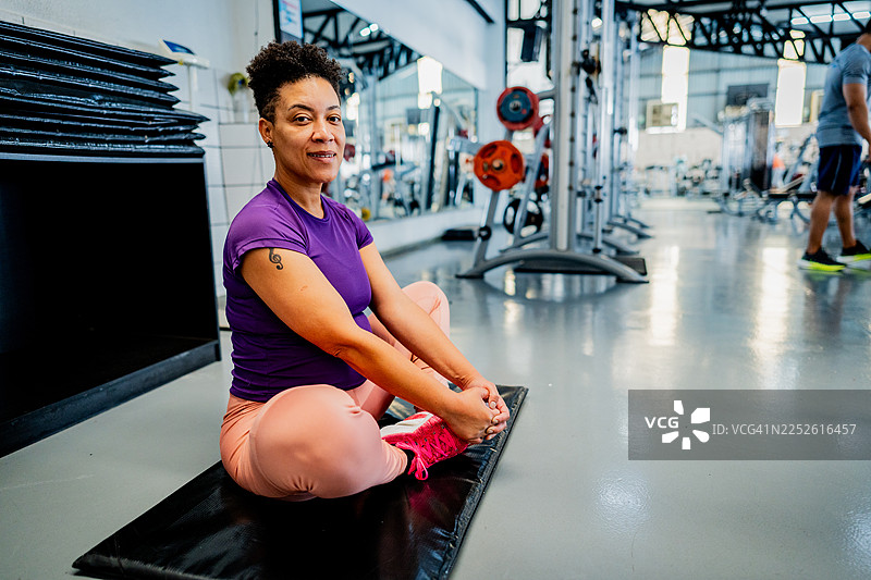 一位成熟的女性在健身房做伸展运动的肖像图片素材